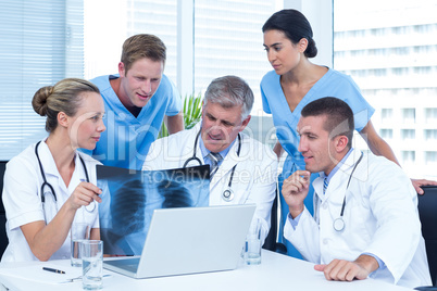 Team of doctors working on laptop and analyzing xray