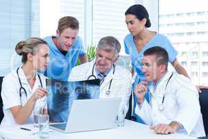 Team of doctors working on laptop and analyzing xray