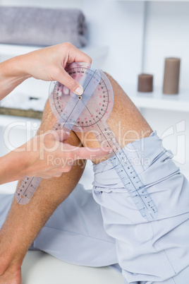 Doctor examining man leg with tool