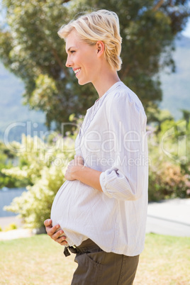 Smiling blonde pregnant hand on his belly