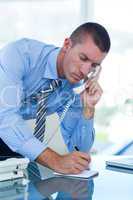 Businessman having a phone call and writing notes