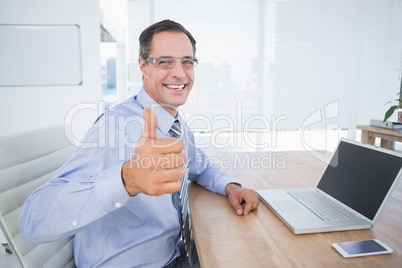 Businessman smiling at camera with thumbs up