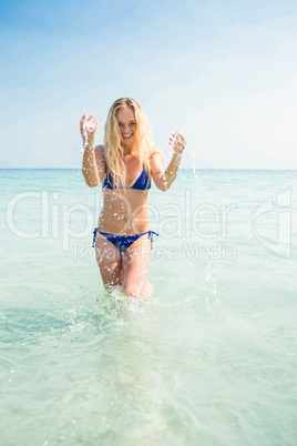 Smiling blonde woman walking into the ocean