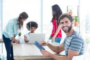 Casual businessman using digital tablet with colleagues behind i