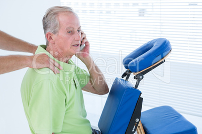 Man having back massage while talking on the phone