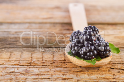 blackberries with spoon on wooden background