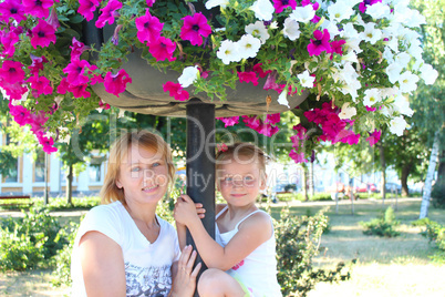 mother and her daughter and many flowers in city park