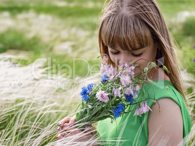 Young sensual girl smelling a bouquet of wildflowers