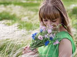 Young sensual girl smelling a bouquet of wildflowers