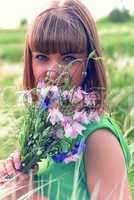 Young sensual girl smelling a bouquet of wildflowers