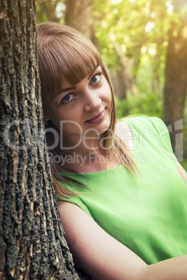 Young sensual girl leaning against a tree