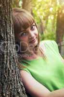 Young sensual girl leaning against a tree
