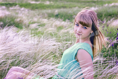 Young sensual girl sits in a grass outdoors