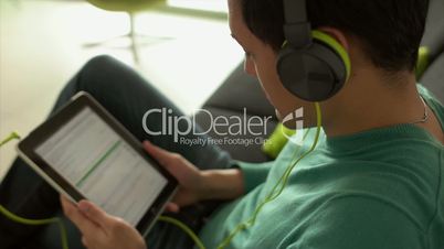 Asian Man Listening Music Podcast On Tablet PC With Earphones