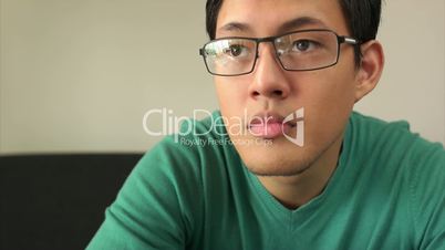 Bored Asian Man Watching TV Changes Channel With Remote