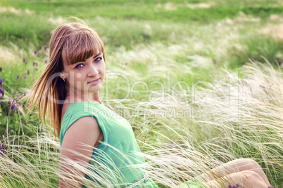 Young sensual girl sits in a grass outdoors