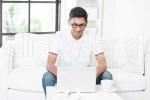 Indian guy using computer at home.