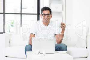Indian male using computer at home.