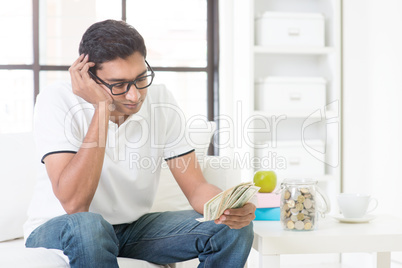 Unhappy Indian guy counting money