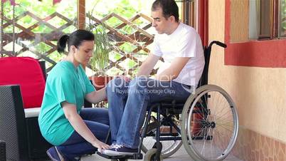 Female nurse consoling sad man sitting in wheelchair