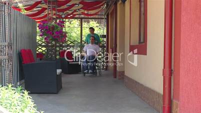 Nurse walking with male patient in a wheelchair