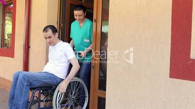 Nurse with young man in wheelchair going for a walk