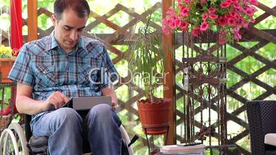 Young man on wheelchair using a tablet computer