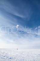 Kiteboarder with blue kite on the snow