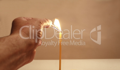 Hand with a match and a candle