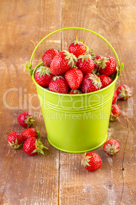 strawberry in a green metal bucket on wooden
