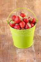 strawberry in a green metal bucket on wooden
