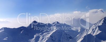 Panorama of snowy mountains in early morning fog