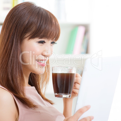 Asian girl drinking coffee while using tablet