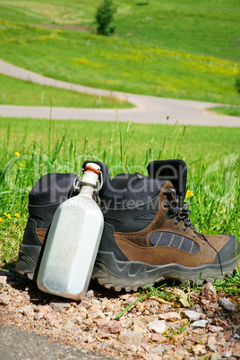 Feldflasche und Wanderstiefel am Wiesenrand