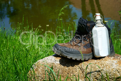 Wanderstiefel und Feldflasche auf einem Felsen