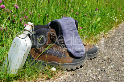 Wanderstiefel mit Strümpfen und Feldflasche am Wegesrand