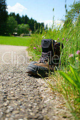 Wanderschuhe am Straßenrand einer Sommerwiese