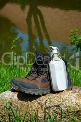 Wanderstiefel und Feldflasche auf einem Felsen