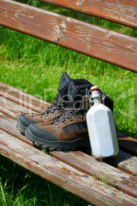 Wanderstiefel und Feldflasche auf einer Bank