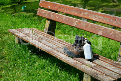 Wanderstiefel mit Feldflasche auf einer Bank