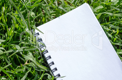 Blank Note Book in Fresh Green Grass Background