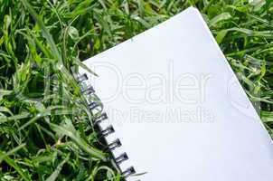 Blank Note Book in Fresh Green Grass Background