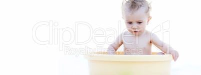 Baby Sitting in a Yellow Bath Basin Against White