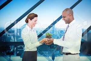 Composite image of business colleagues holding plant together