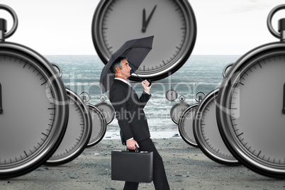 Composite image of businessman pushing the wind with umbrella