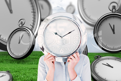 Composite image of businesswoman hiding face with clock