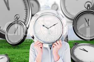 Composite image of businesswoman hiding face with clock