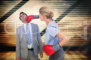 Composite image of businesswoman punching colleague with boxing