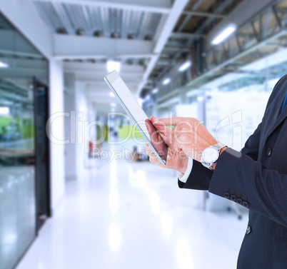 Composite image of businessman in suit using digital tablet