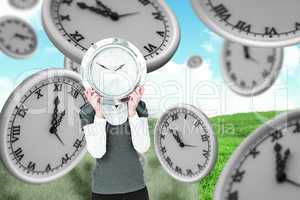 Composite image of woman holding clock in front of her head